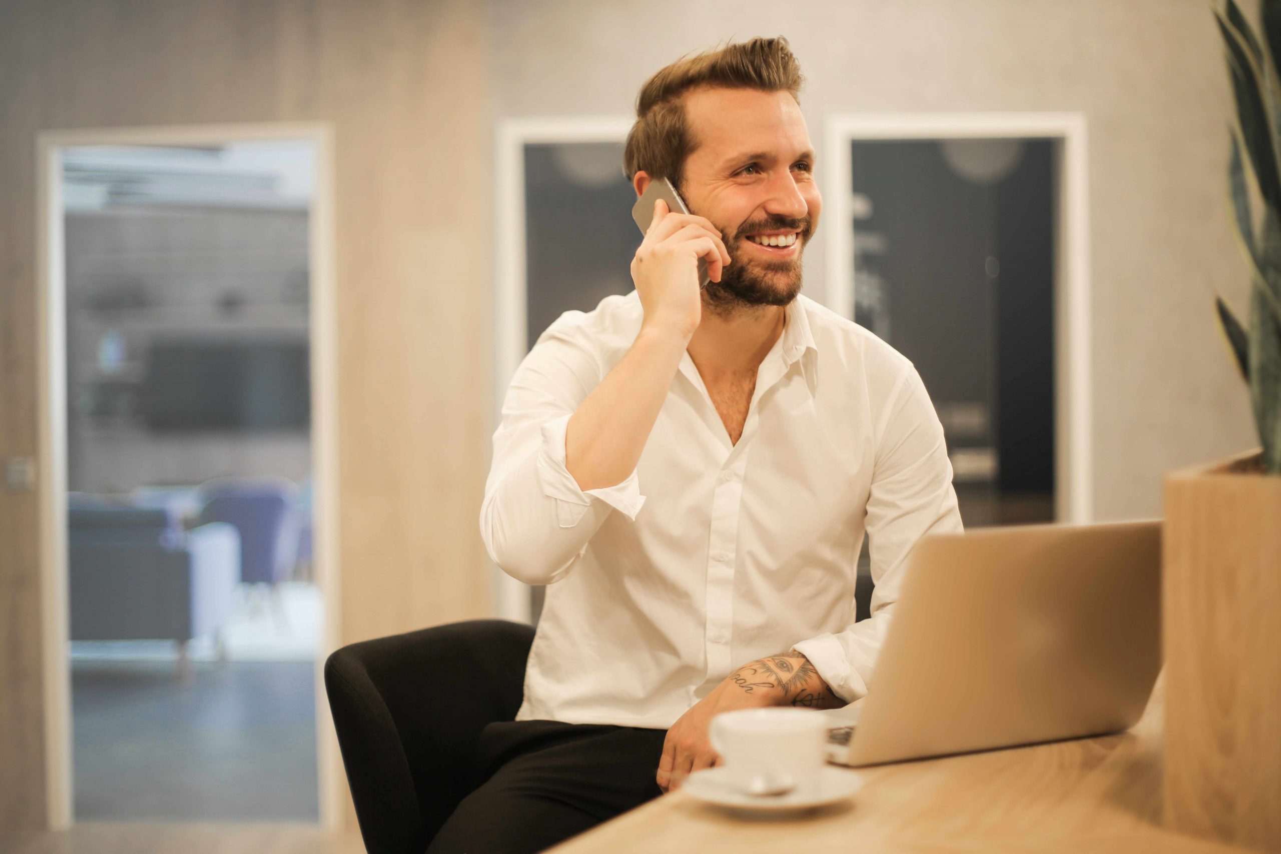 Smart working - uomo davanti a pc al telefono sorridente